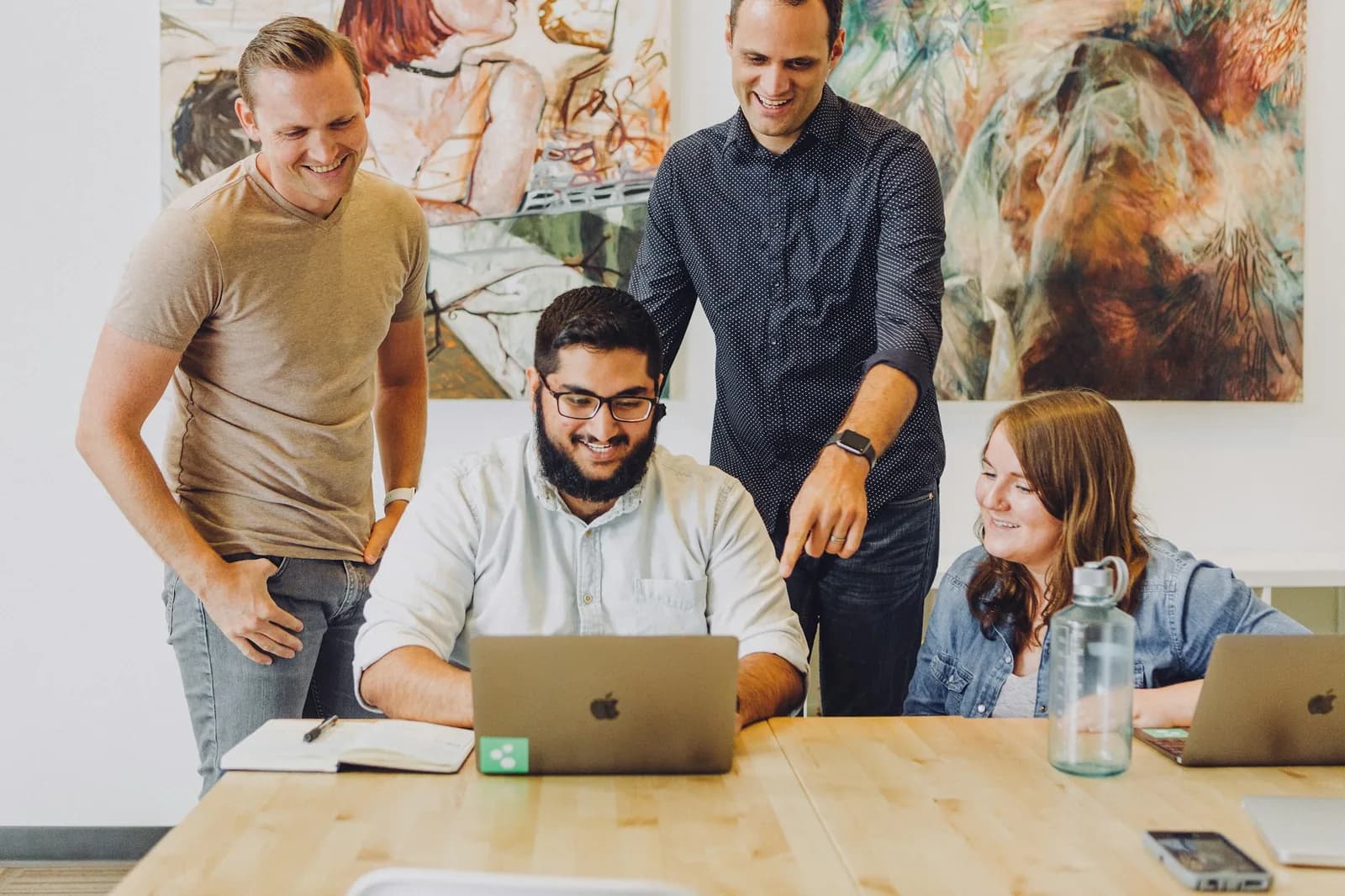 An agency team gathered around a laptop, smiling as they review work together